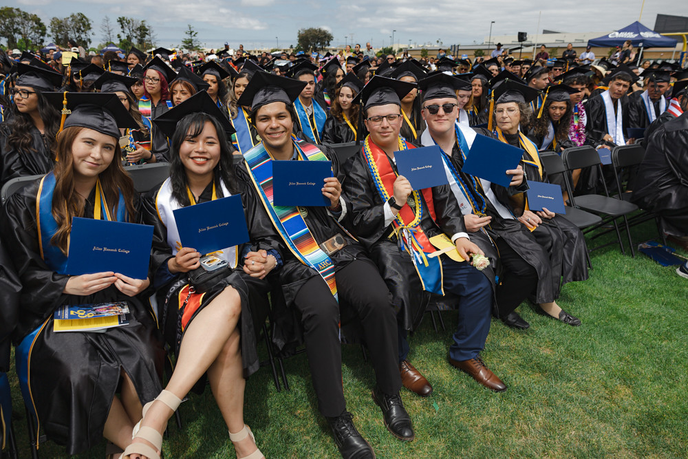 Hancock graduates in caps and gowns hold up their degrees.